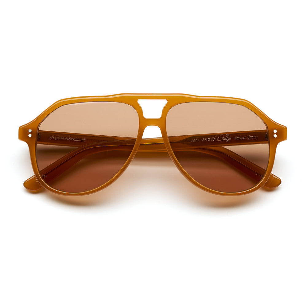 A pair of aviator-style sunglasses with a translucent amber-brown frame and matching brown lenses, shown from the front on a clean white background.