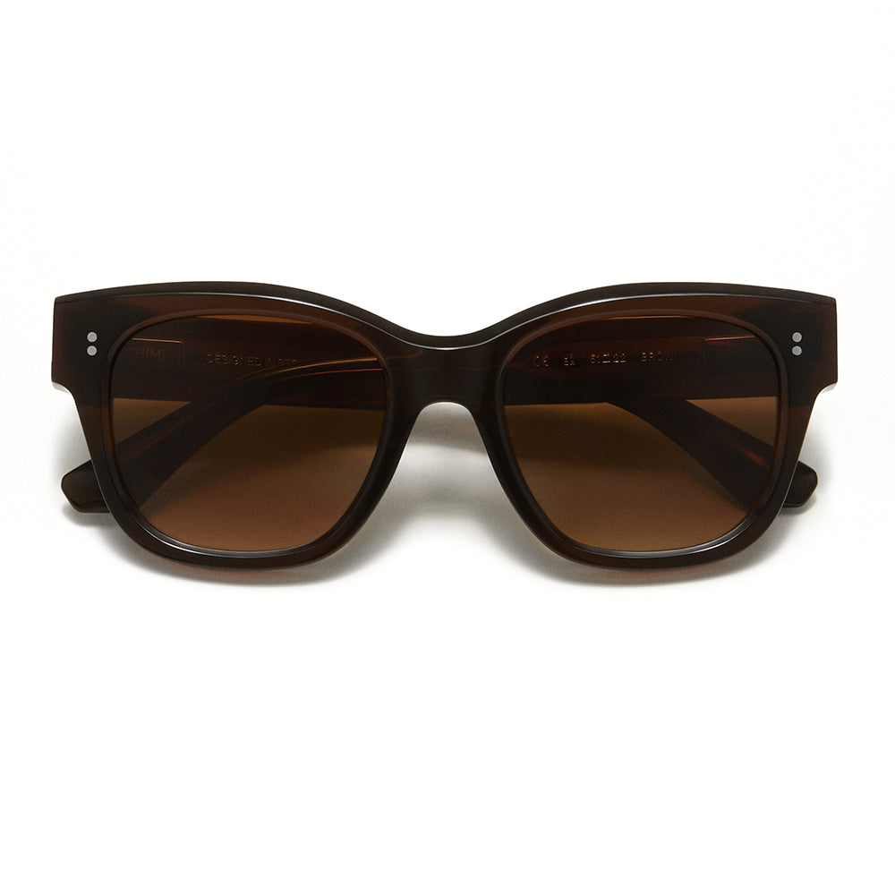 A pair of cat-eye sunglasses with a dark brown translucent acetate frame and matching brown gradient lenses, shown against a plain white background.